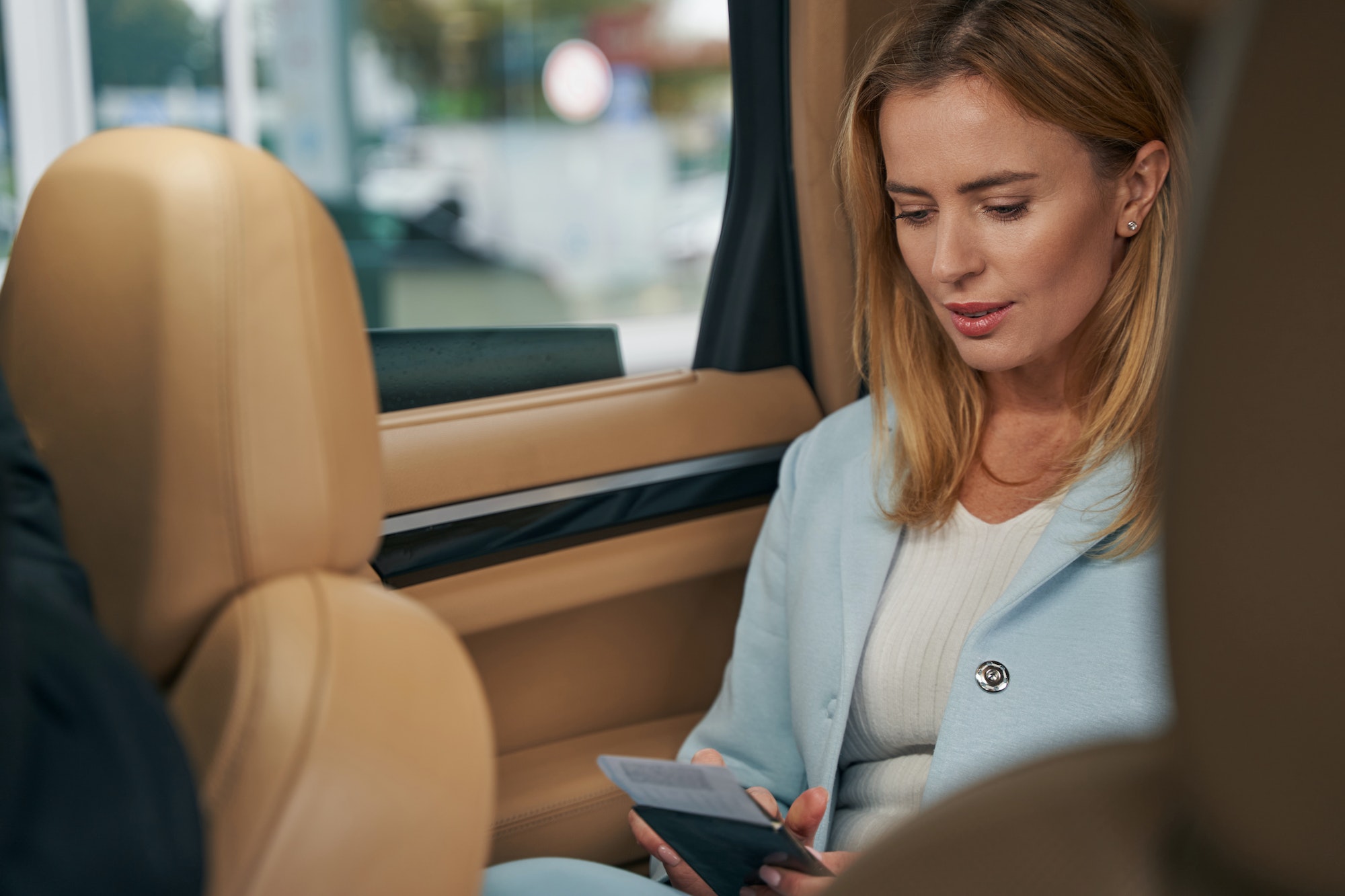 Woman with boarding ticket sitting in car